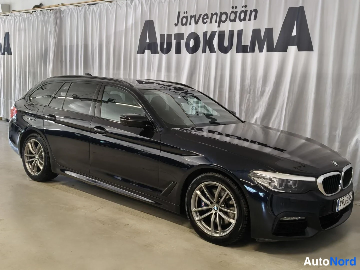 Etuviisto, nokka oikealle: Musta BMW-maasturi kolmesta neljästä nähtynä edestä oikealta, keulakori ja molemmat kyljet kuvassa.