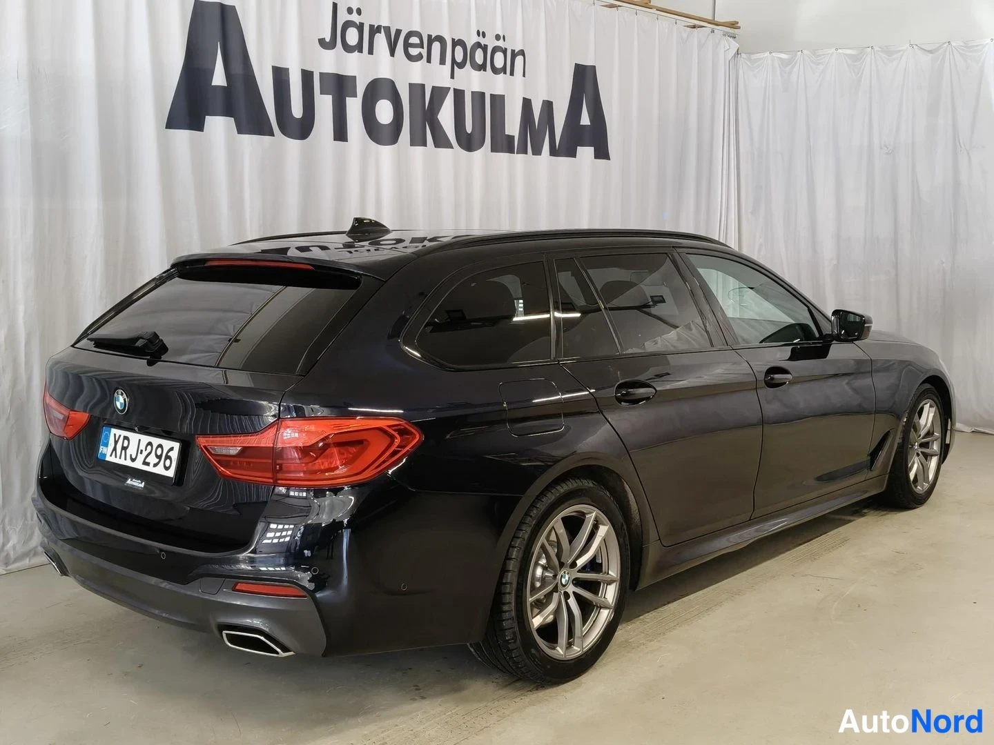 Takaviisto: Musta farmariauto kolmesta neljästä takaa vasemmalta, perä ja kylki näkyvät.