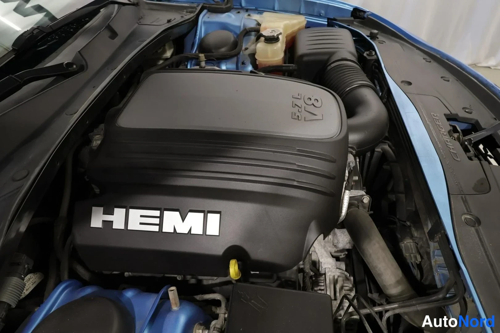 Muu: Moottoritilan ylänäkymä: HEMI-merkitty suojakansi ja 5.7L V8-teksti imusarjan päällä.