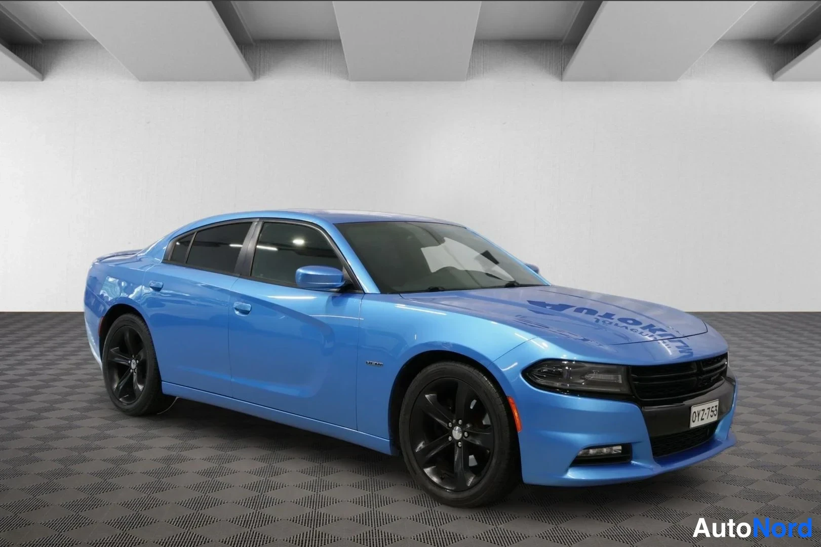 Etuviisto, nokka oikealle: Sininen Dodge Charger etuviistosta oikealta kuvattuna sisätilassa, rekisterikilpi.