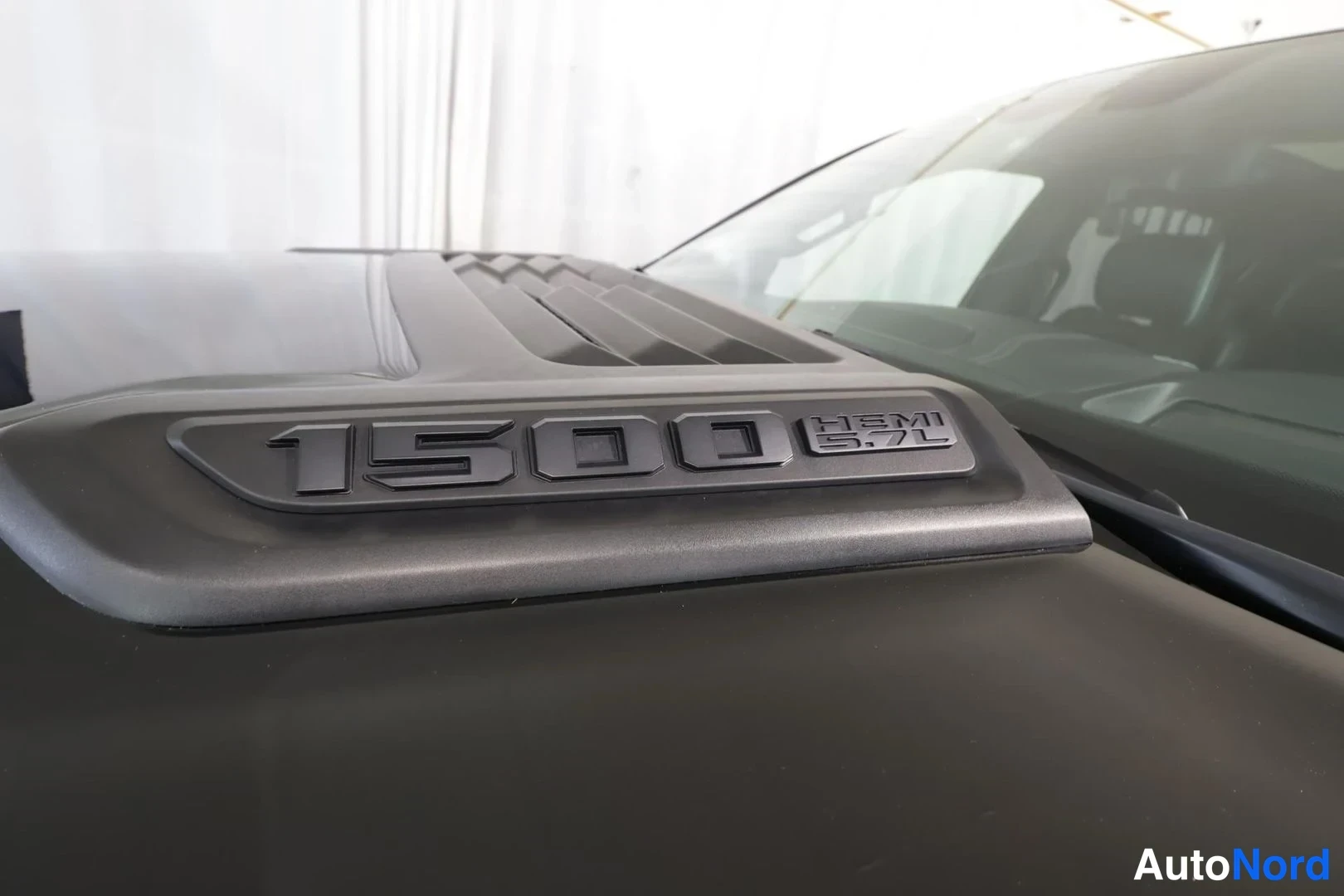 Yksityiskohta: Lähikuva auton konepeltiin integroidusta ilmanottoaukosta, jossa on teksti 1500 HEMI 5.7L.
