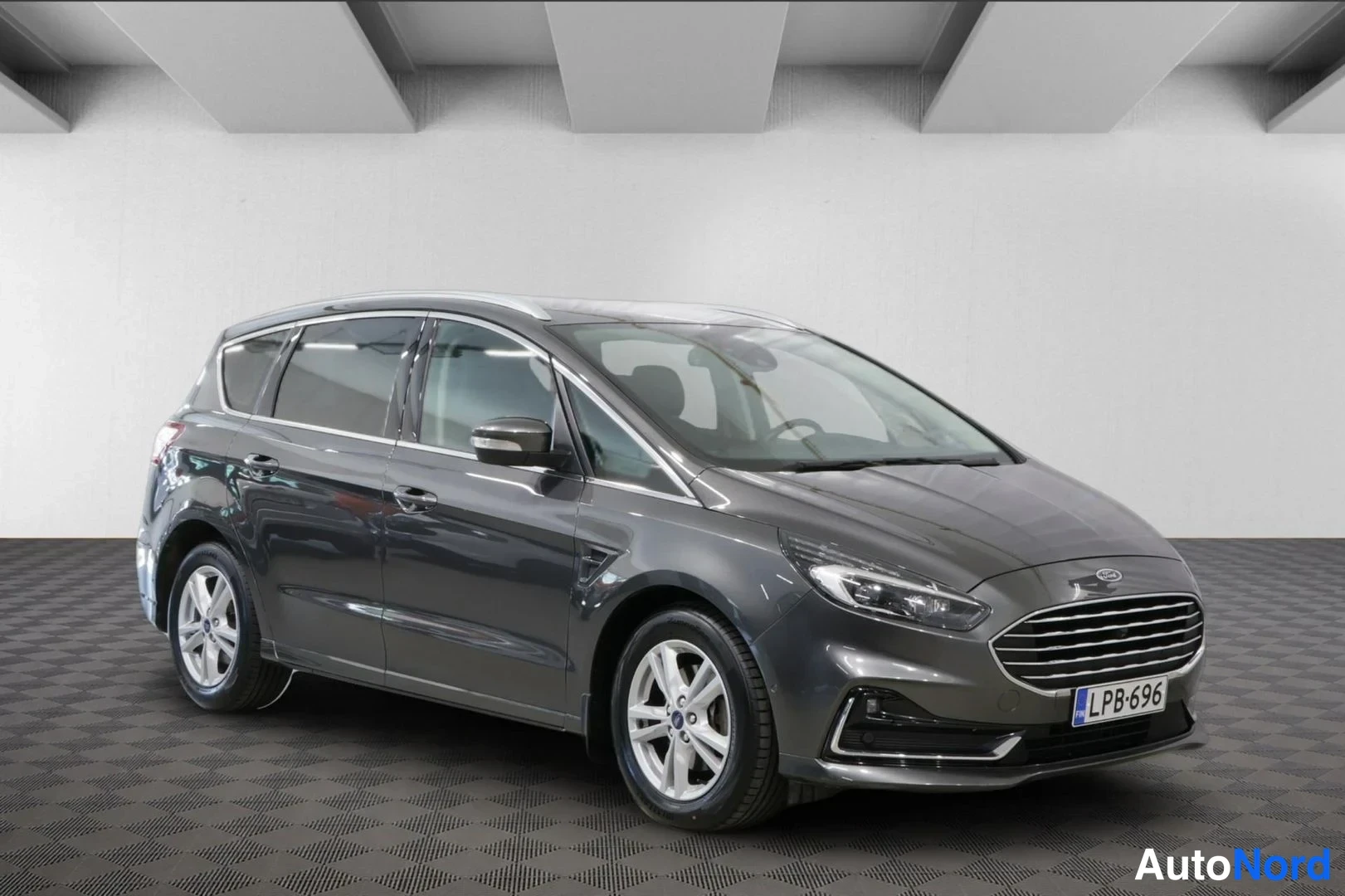 Etuviisto, nokka oikealle: Tummanharmaa Ford S-MAX etukolmasosa oikealta, rekisterikilpi, kuvattuna sisätiloissa.