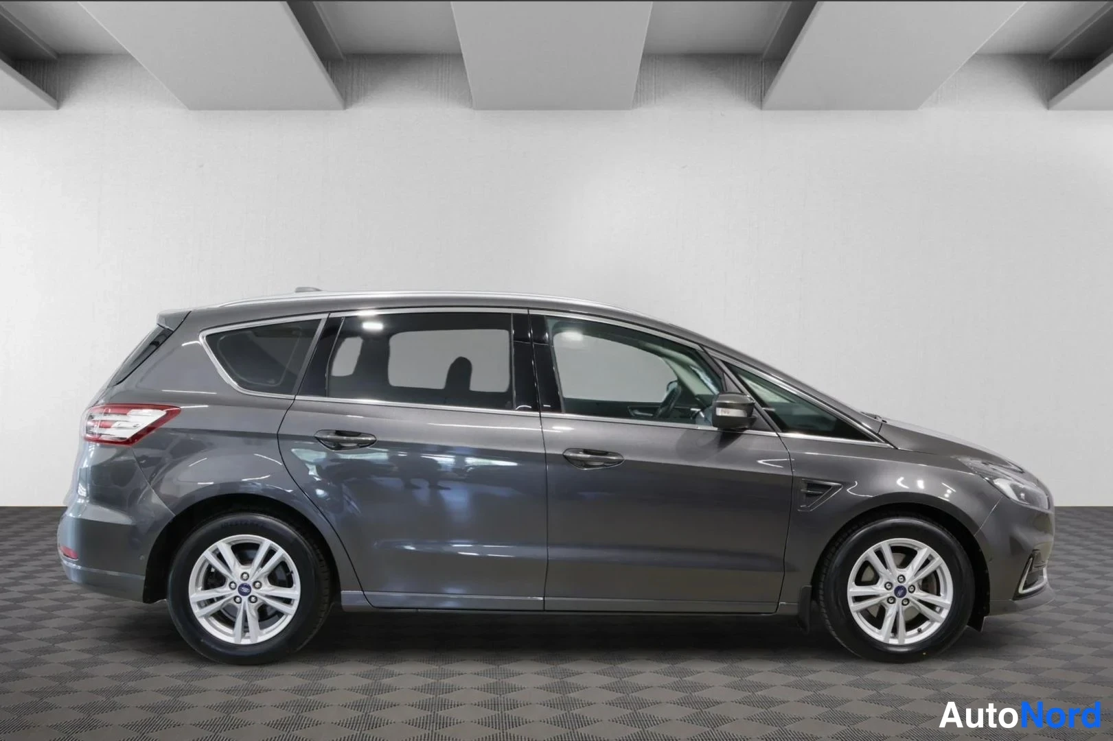 Sivulta: Tummanharmaan Ford S-MAX -henkilöauton sivuprofiili sisätiloissa, molemmat sivut ja katto näkyvissä.