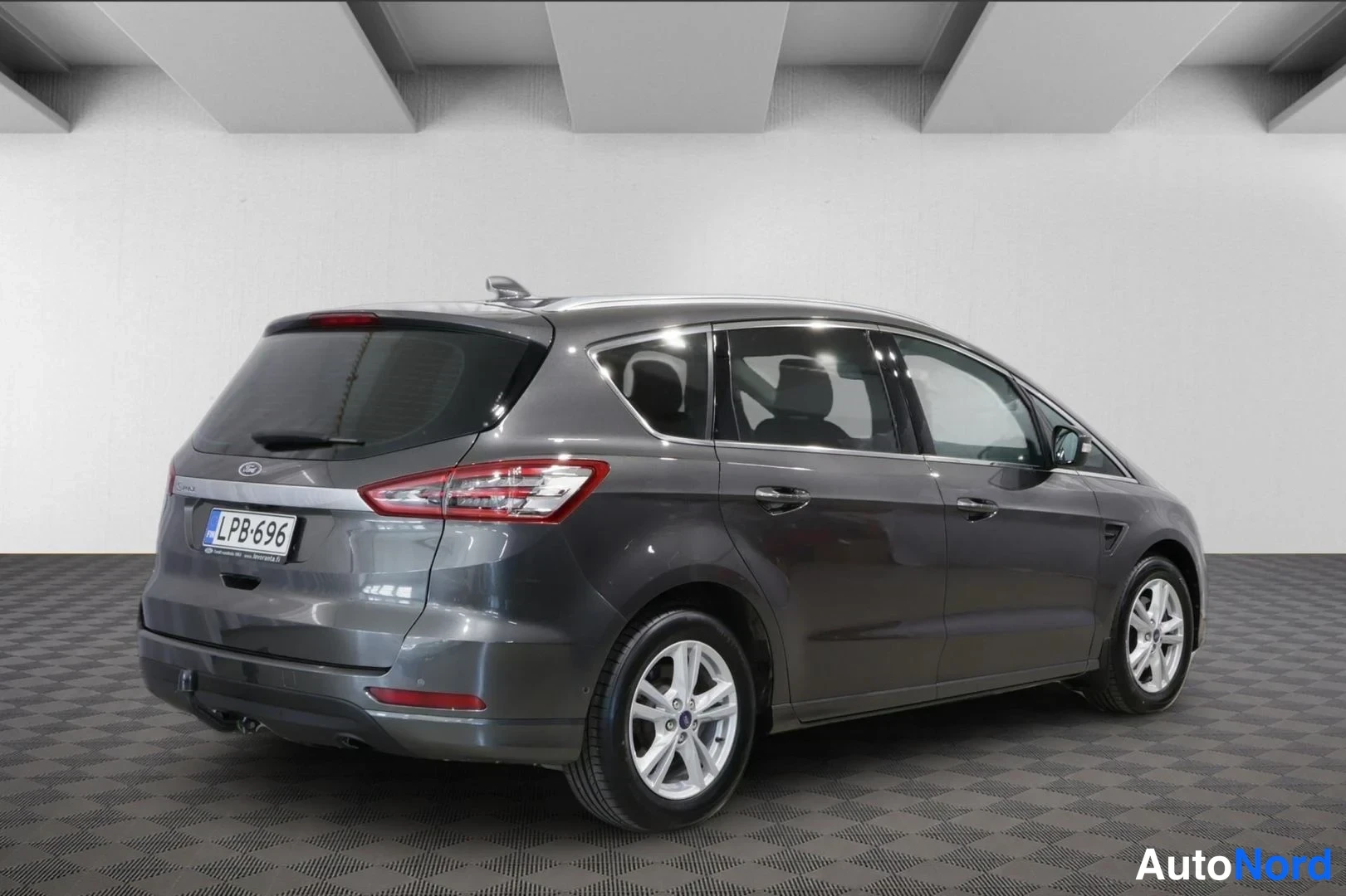 Takaviisto: Tummanharmaan Ford S-MAX:n takakolmasosa, rekisterikilpi, kuvattuna sisätiloissa.