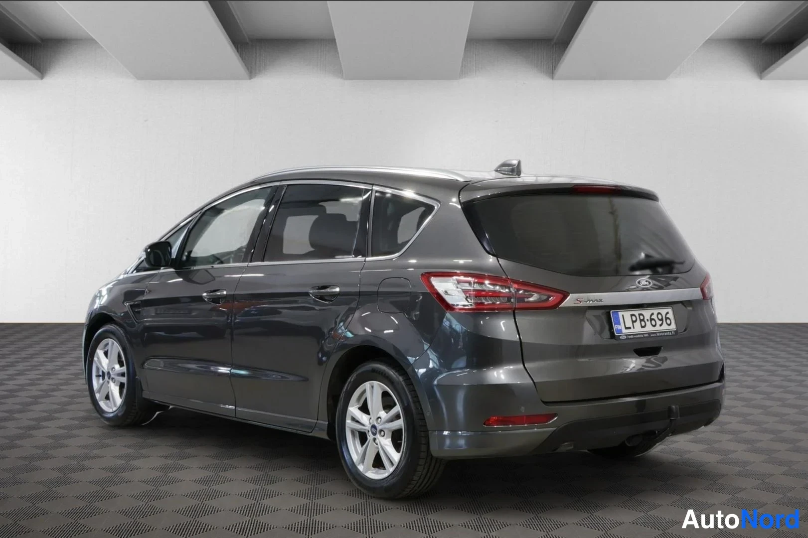 Takaviisto: Kuvassa on hopeanharmaa Ford S-Max. Takatunneli ja sivupaneelit ovat näkyvissä. Rekisterikilpi lukee. Kevyesti metalliset vanteet ovat nähtävissä.