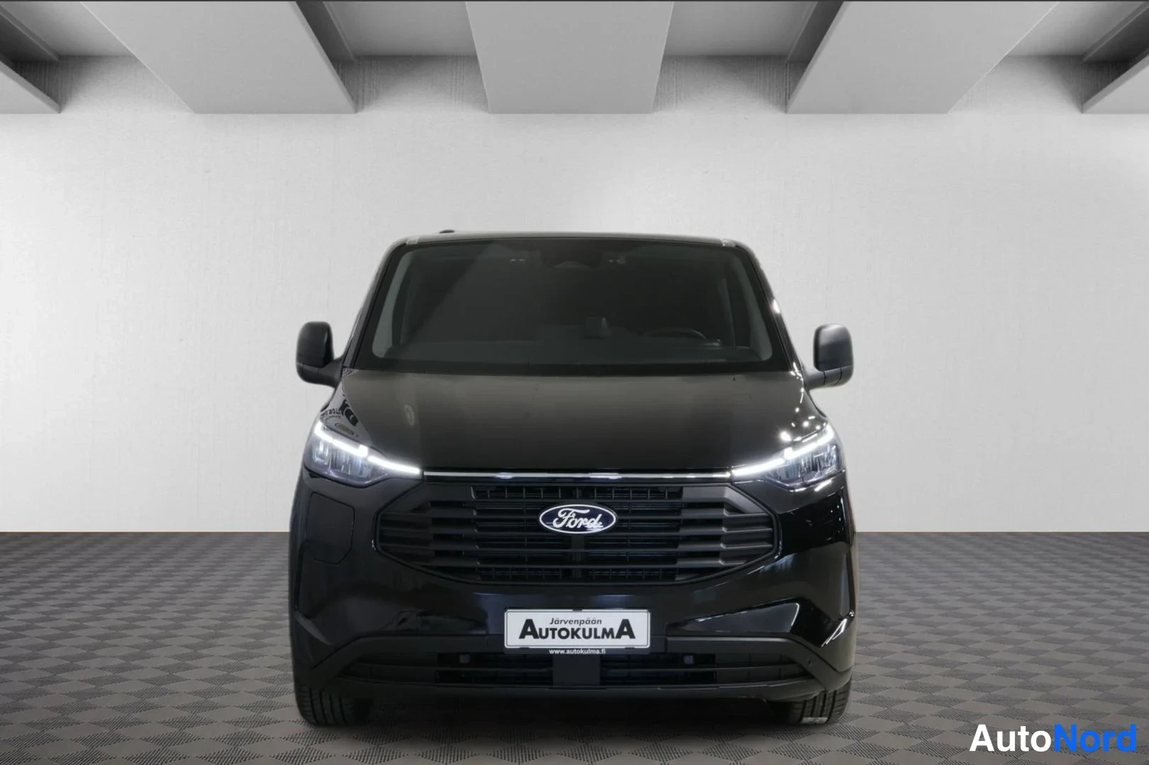 Edestä: Musta pakettiauto suoraan edestä kuvattuna, etusäleikkö ja Ford-merkki näkyvissä.
