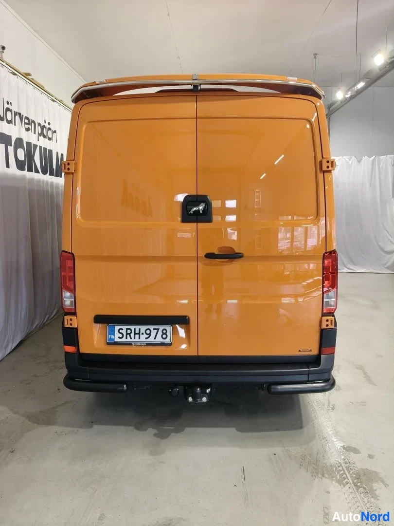 Takaa: MAN TGE -pakettiauto suoraan takaa kuvattuna, oranssi kori, rekisterikilpi ja takaluukun kahva.