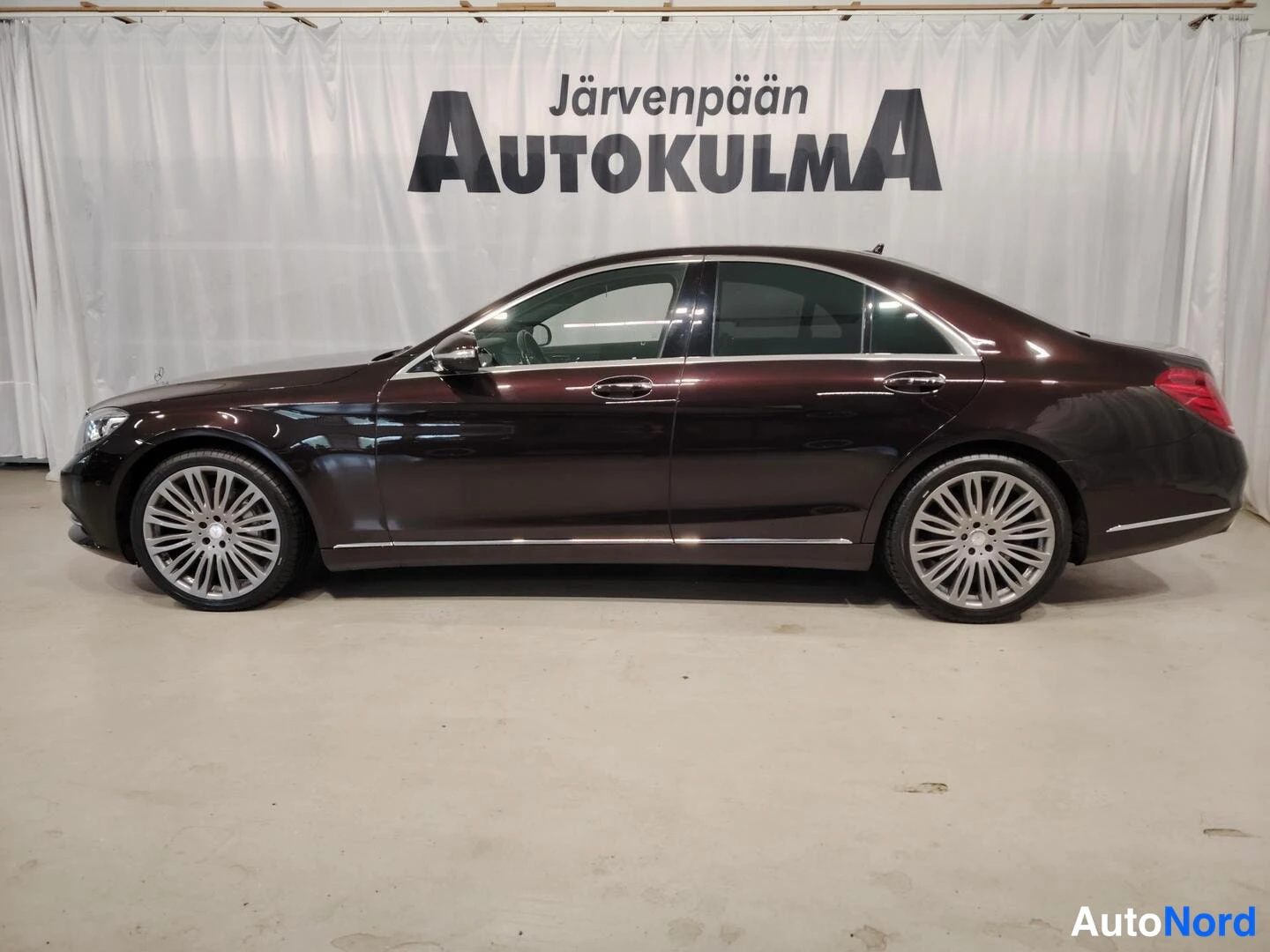 Sivulta: Mercedes-Benz S-luokan sedan sivuprofiili kokonaan oikealta vasemmalle kuvattuna. Neljä ovea, kroomiset ikkunalistat ja harmaat monihaaravanteet näkyvät.