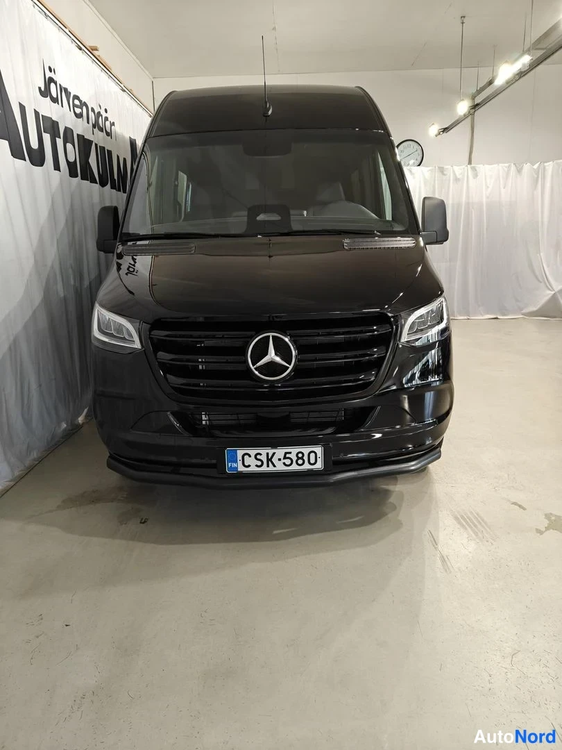 Edestä: Etunäkymä mustasta Mercedes-Benz Sprinter -pakettiautosta, rekisteritunnus.