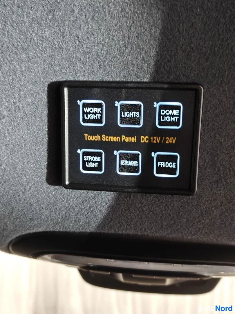 Muu: Suurennos kosketusnäytöllisestä kytkinpaneelista, jossa painikkeet Work Light, Lights, Dome Light, Strobe Light, Instruments ja Fridge sekä teksti Touch Screen
