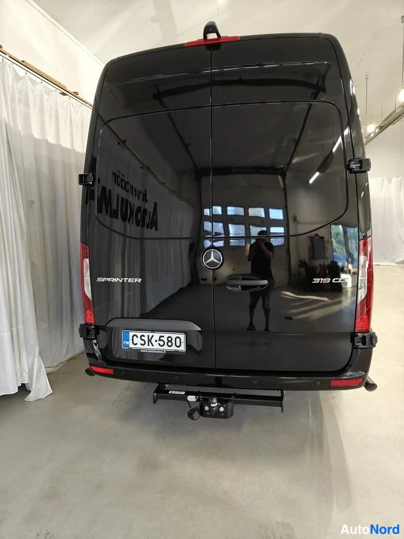 Takaa: Takanäkymä mustasta Mercedes-Benz Sprinter -pakettiautosta, jossa vetokoukku ja tekstit SPRINTER ja 319 CDI.