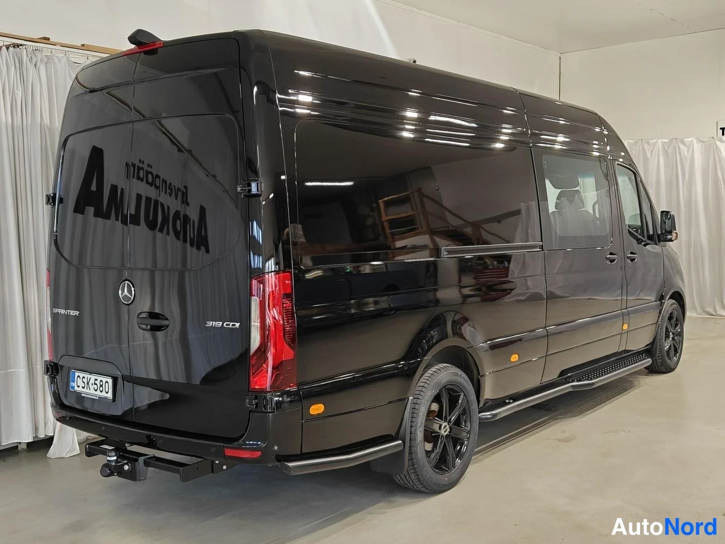 Takaviisto: Musta Mercedes-Benz Sprinter 319 CDI -pakettiauto takana kolmen neljänneksen kulmasta. Rekisterinumero ja perämittari selkeästi näkyvissä.