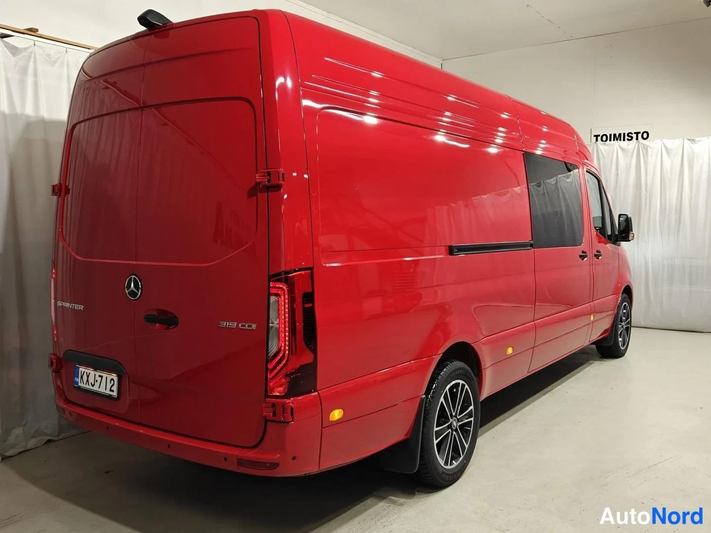 Takaviisto: Punaisen Mercedes-Benz Sprinterin takaosa ja oikea kylki sivusta, takavalo, Mercedes-tähti ja rekisterikilpi näkyvät.