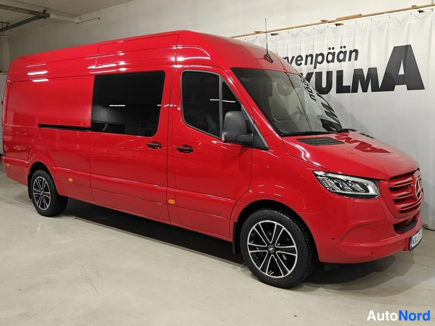 Etuviisto, nokka oikealle: Punainen Mercedes-Benz Sprinter -pakettiauto kolmesta neljänneksestä edestä oikealta, keulavalo ja kylki näkyvät sisätiloissa.