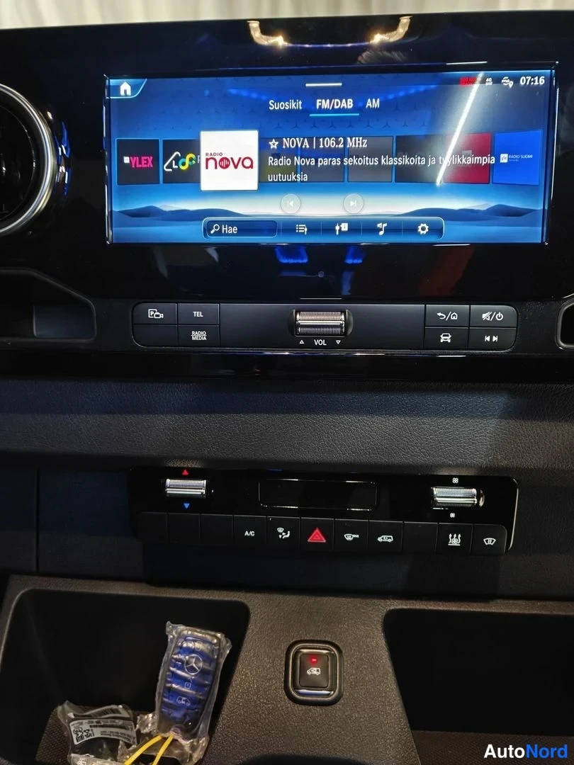 Sivulta: Kojetaulun keskikäyttöpaneeli, infotainment-näyttö radioasemalla Radio Nova 106.2 MHz ja sen alla USB-portit sekä ilmastointinäppäimet.