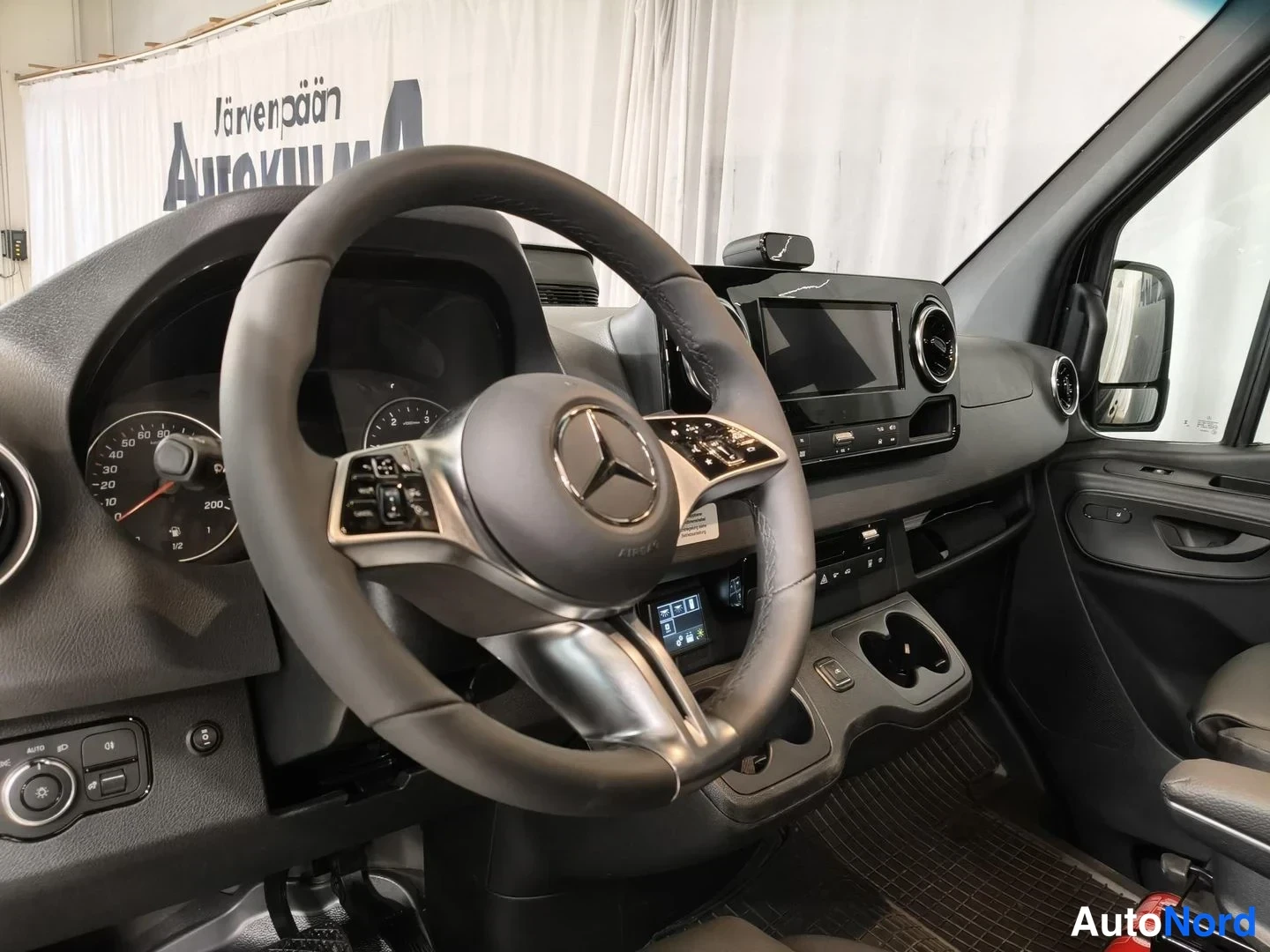 Yksityiskohta: Mercedes-henkilöauton ohjaamo: ohjauspyörä, mittaristo ja kojelautanäyttö.