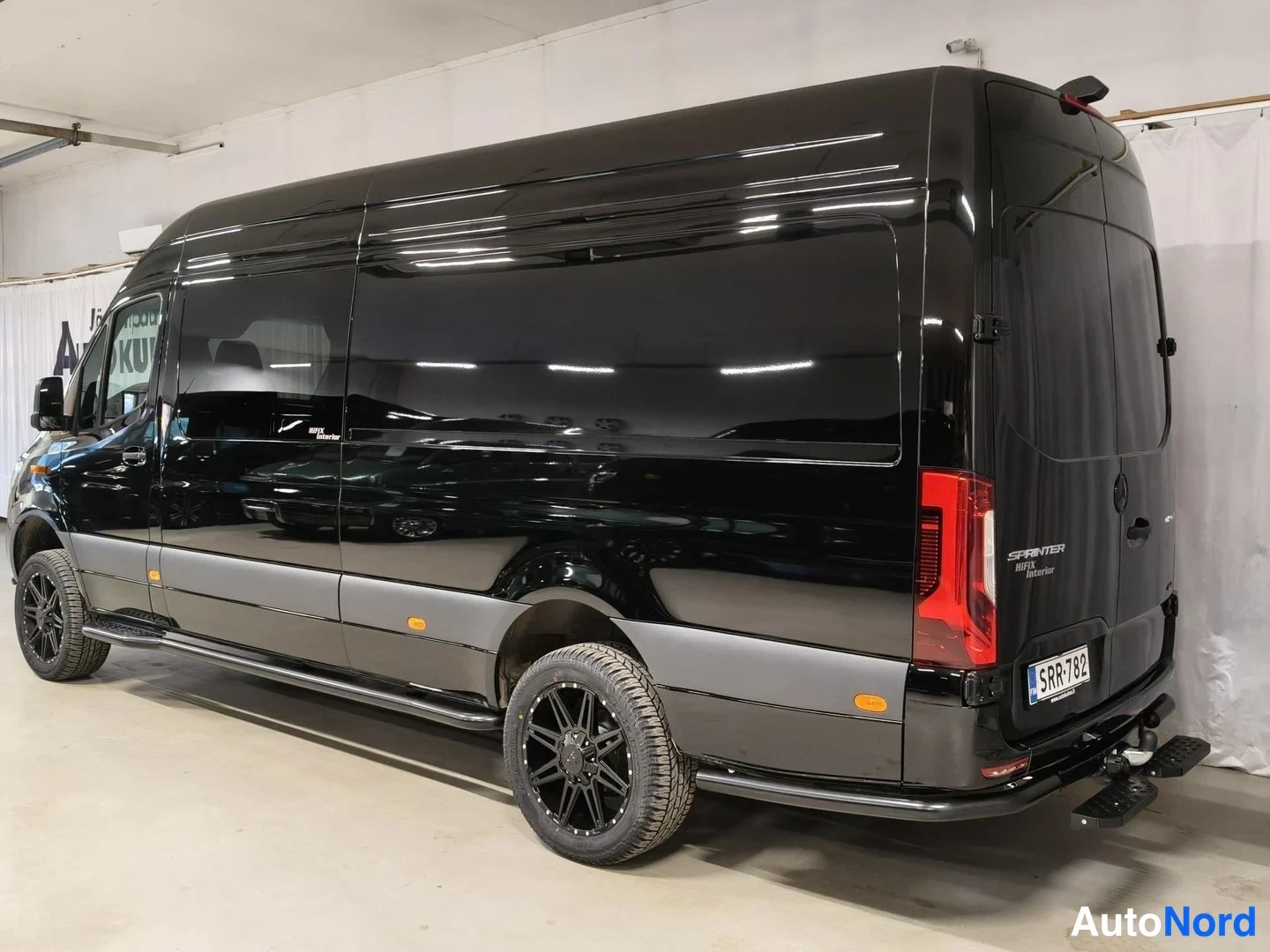 Takaviisto: Musta Mercedes-Benz Sprinter -pakettiauto takaviistosta kuvattuna sisätilassa.