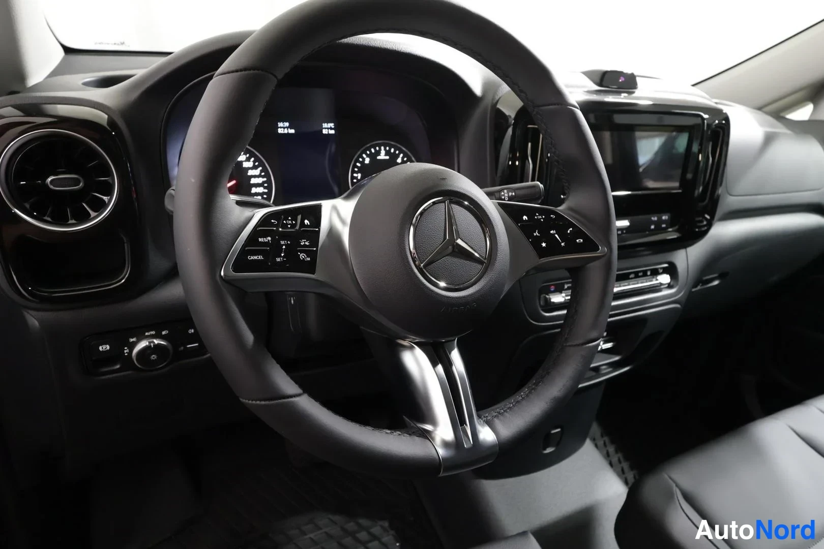 Muu: Lähikuva Mercedes-ohjauspyörästä ja mittaristosta, monitoiminapit ja näyttö näkyvissä.