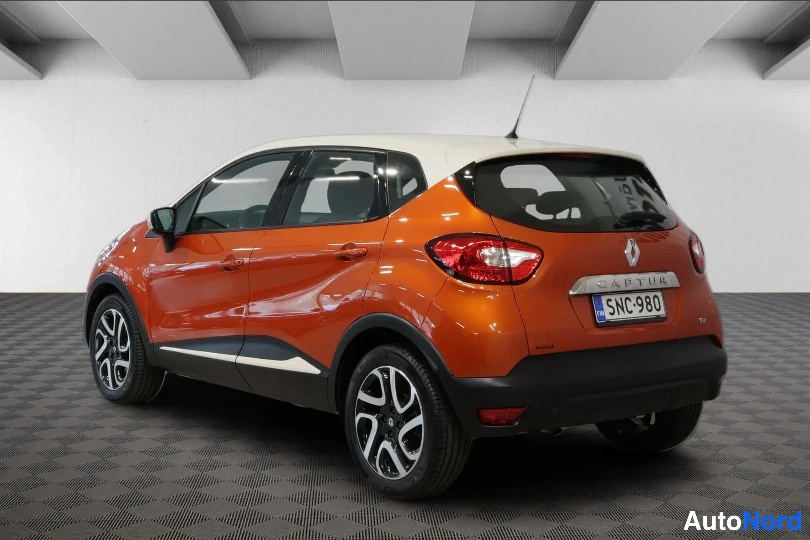 Takaviisto: Oranssi Renault Captur takaa kolmelta neljännekseltä, rekisterikilpi ja CAPTUR-teksti kannella.