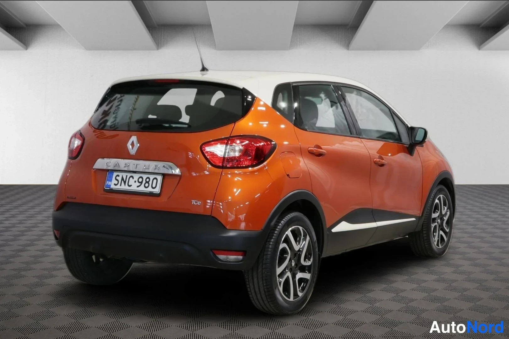 Takaviisto: Renault Captur takaa vinosti vasemmalta kuvattuna, oranssi kori ja valkoinen katto, rekisteritunnus, CAPTUR-teksti takaluukussa ja TCe-merkintä.