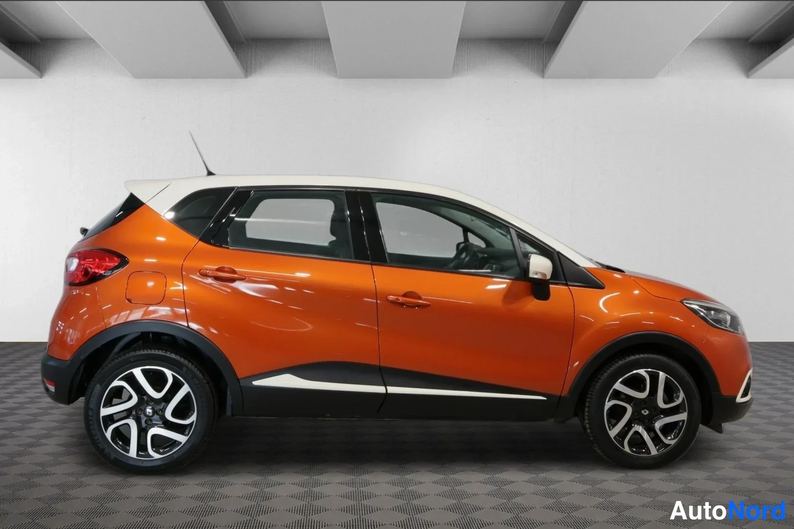 Sivulta: Renault Captur sivulta kuvattuna, oranssi kori ja valkoinen katto, mustat kynnykset ja kaksiväriset alumiinivanteet.