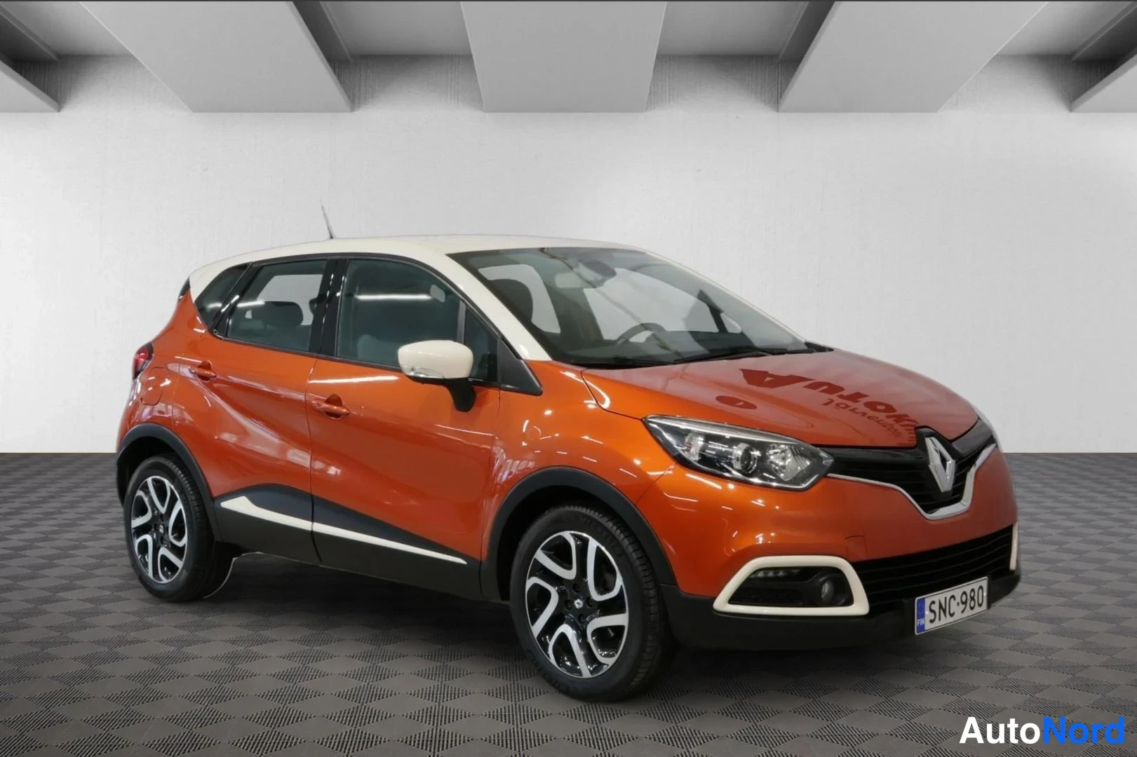 Etuviisto, nokka oikealle: Renault Captur etureisista oikealta kuvattuna, oranssi kori, valkoinen katto ja peilit, rekisteritunnus.