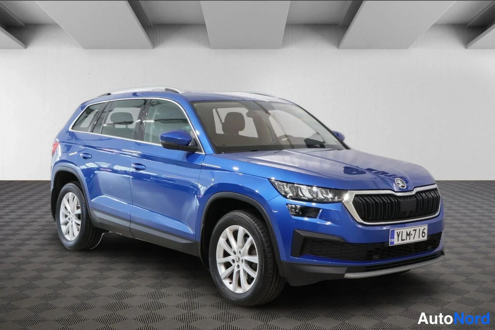 Etuviisto, nokka oikealle: Sininen Skoda Kodiaq -SUV kuvattu kolmeneljännesnäkymästä edestä oikealta studioympäristössä, rekisterikilpi.