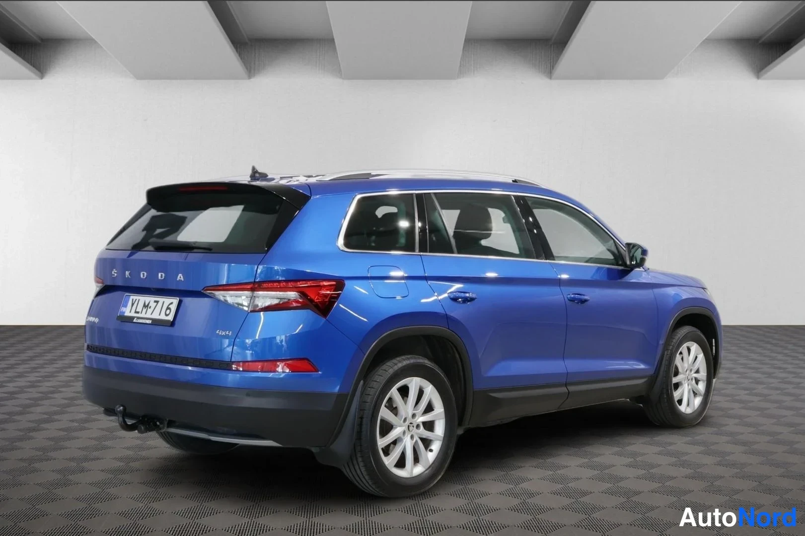 Takaviisto: Taka kolmeneljännesnäkymä sinisestä ŠKODA Kodiaq -SUV:sta, rekisterikilpi, vetokoukku näkyvissä takapusketrin alla.