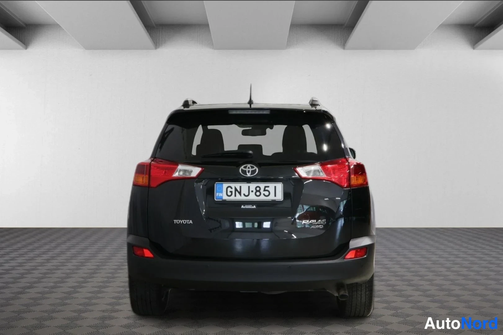 Takaa: Mustan Toyota RAV4:n takanäkymä sisätiloissa; rekisterikilpi, RAV4 AWD-merkintä takakannessa.