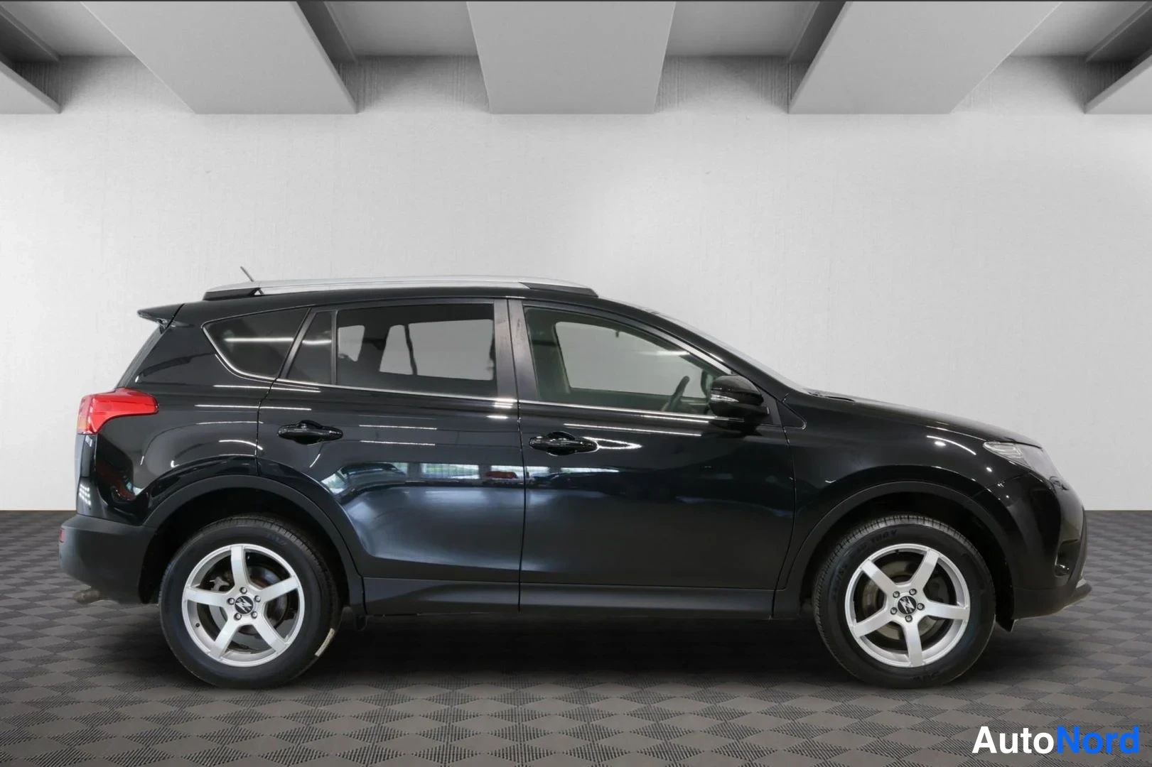 Sivulta: Mustan Toyota RAV4:n sivuprofiili oikealta; viisiovinen korirakenne, kattotelineet ja hopeat vanteet.