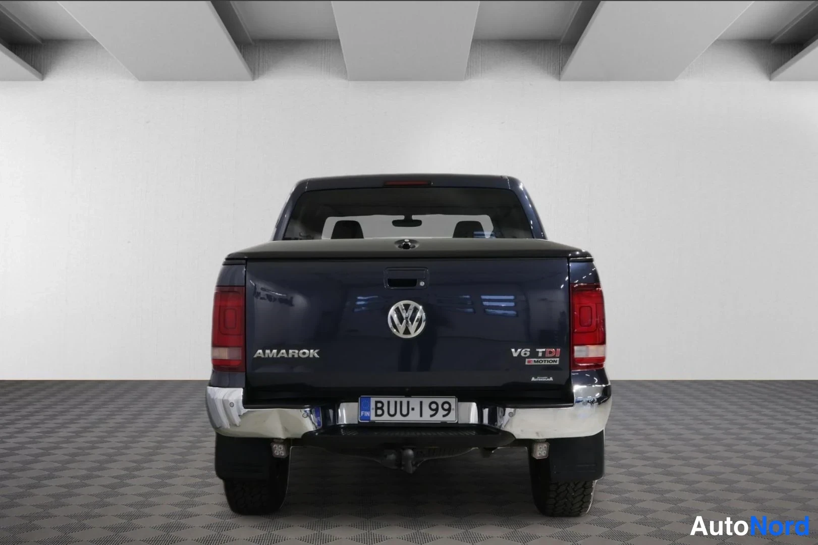 Takaa: Tummansinisen Volkswagen Amarok -lava-auton takaosa suoraan takaa; kylkiluvut AMAROK ja V6 TDI sekä rekisterikilpi.