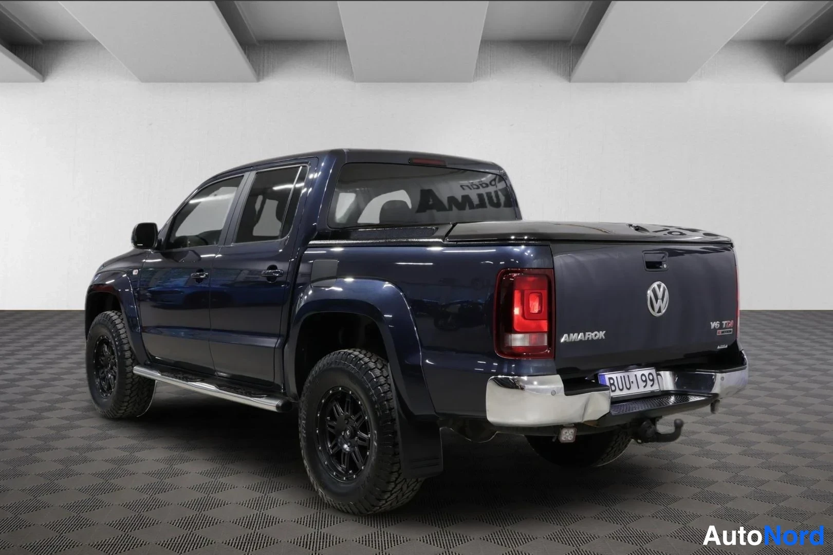 Takaviisto: Tummansinisen Volkswagen Amarok -lava-auton takakolmasosa vasemmalta, AMAROK-merkintä ja rekisterikilpi lavan takaseinässä.