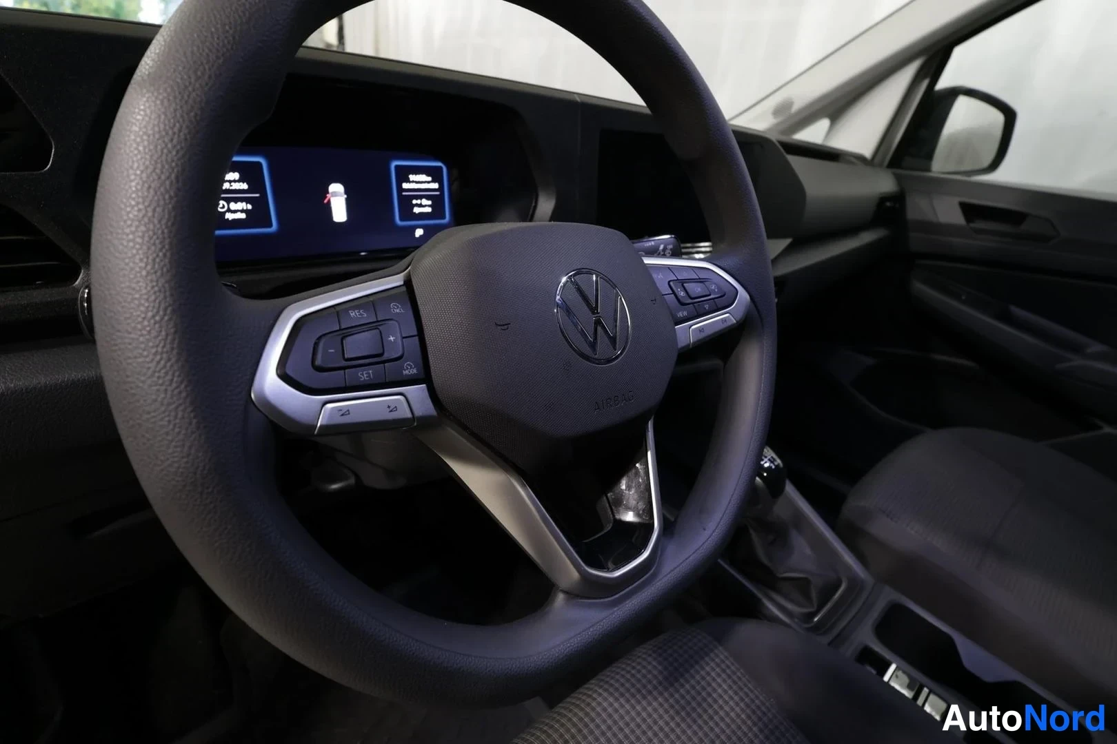 Edestä: Lähikuva ohjauspyörästä, jossa VW-logo, ja digitaalisesta mittaristosta.