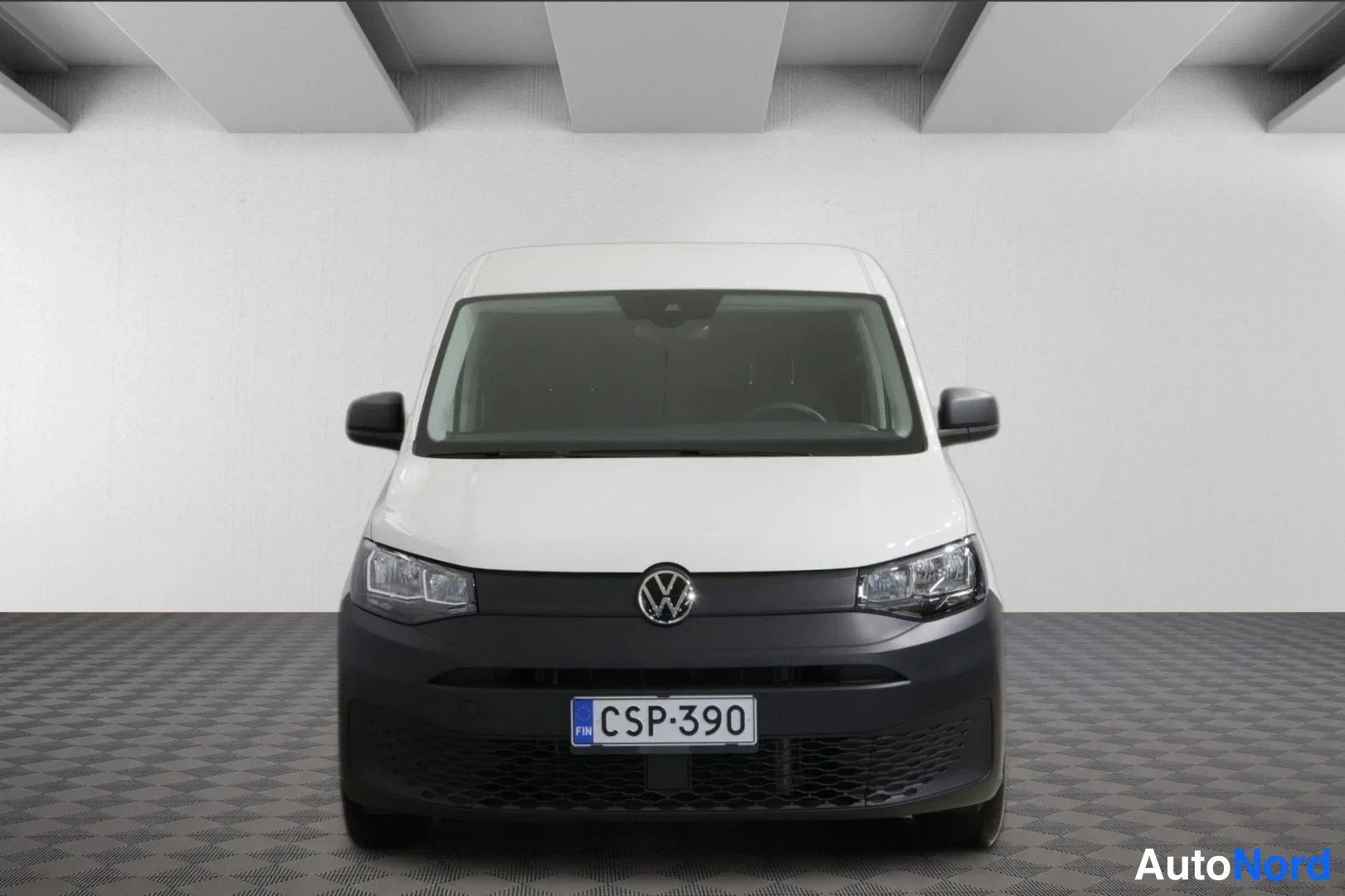 Edestä: Suoraan edestä kuvattu valkoinen pakettiauto, jonka keulassa on VW-merkki ja rekisterikilpi.