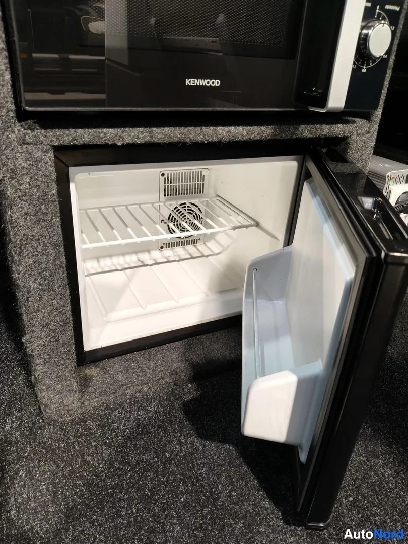 Muu: Kenwood-merkkinen mikroaaltouuni ja sen alla avattu jääkaappi valkoisilla hyllyillä.