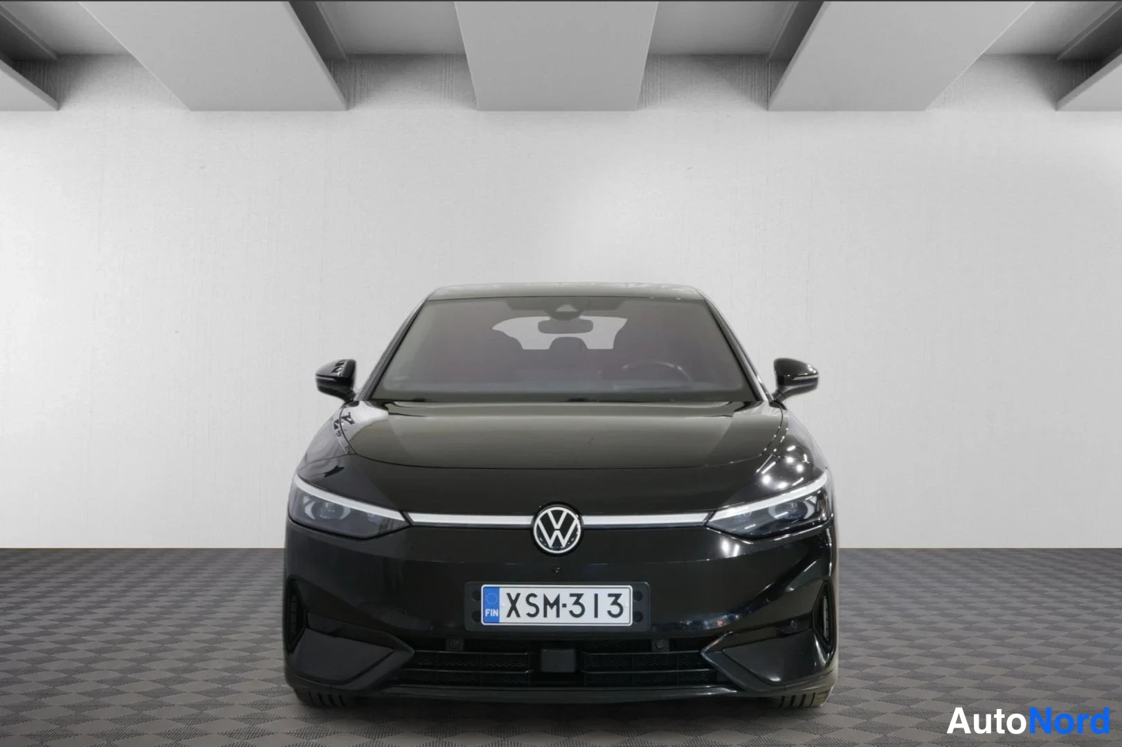 Edestä: Mustan Volkswagen ID.7:n suora etukuva studiovalkoisella taustalla, rekisteritunnus.