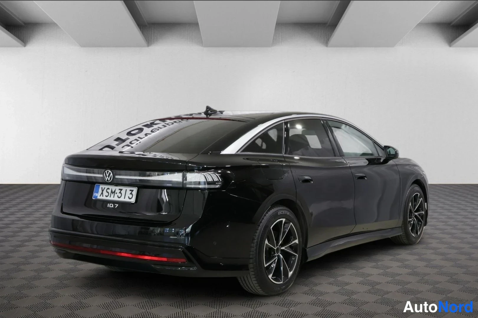 Takaviisto: Mustan Volkswagen ID.7:n takakulmakuva studiovalkoisella taustalla, rekisteritunnus.