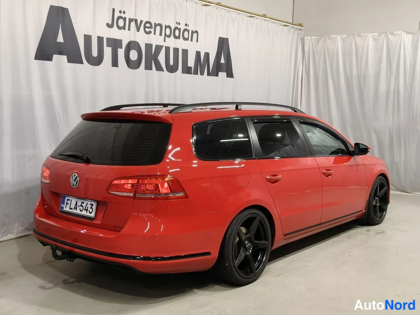 Takaviisto: Punainen farmari kolmesta takaa sivulta; mustat vanteet, rekisterikilpi, kattokaiteet.