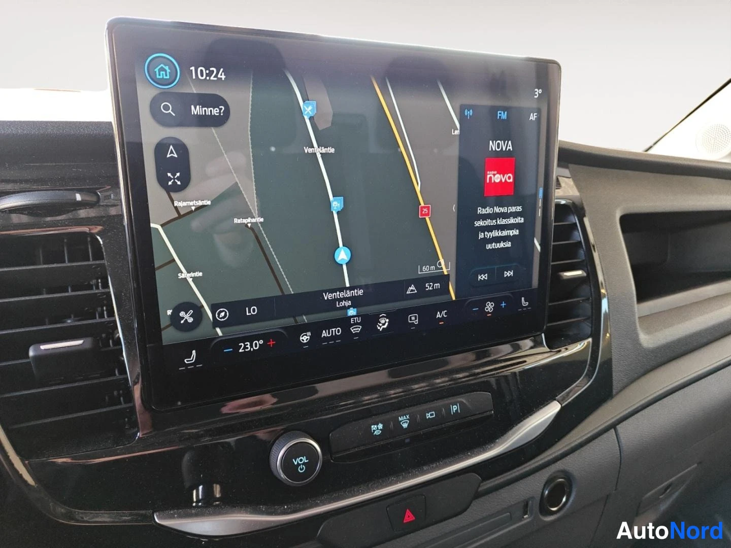 Yksityiskohta: Takin infotainment-näyttö näyttää navigointikarttaa ja Radio Nova -sovellusta, alla ilmastointiautomaatio ja VOL-nappi.
