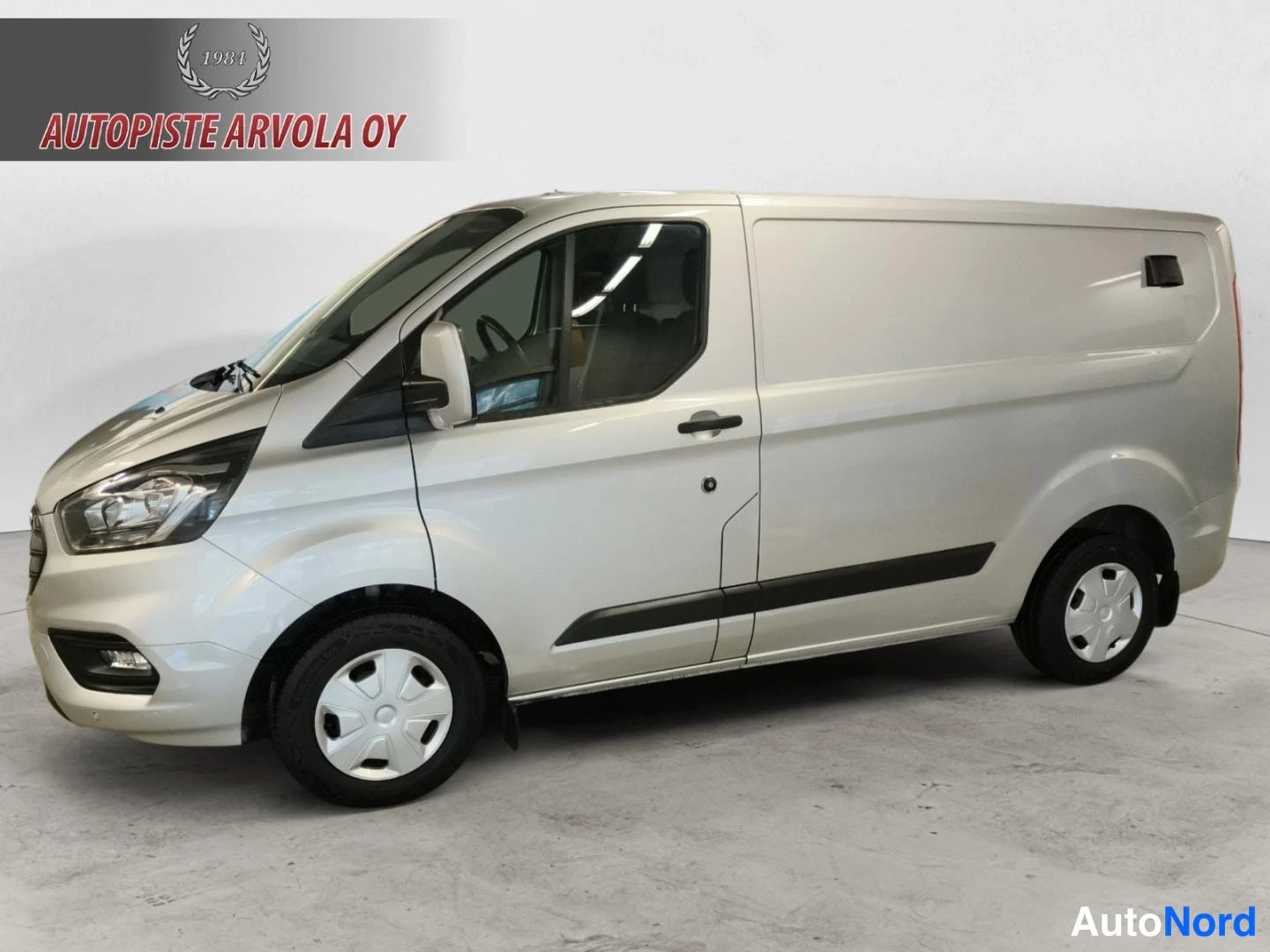 Etuviisto, nokka vasemmalle: Ford Transit Custom -pakettiauto edestä vasemmalta kolmannelta, valkoinen koriratkaisu.