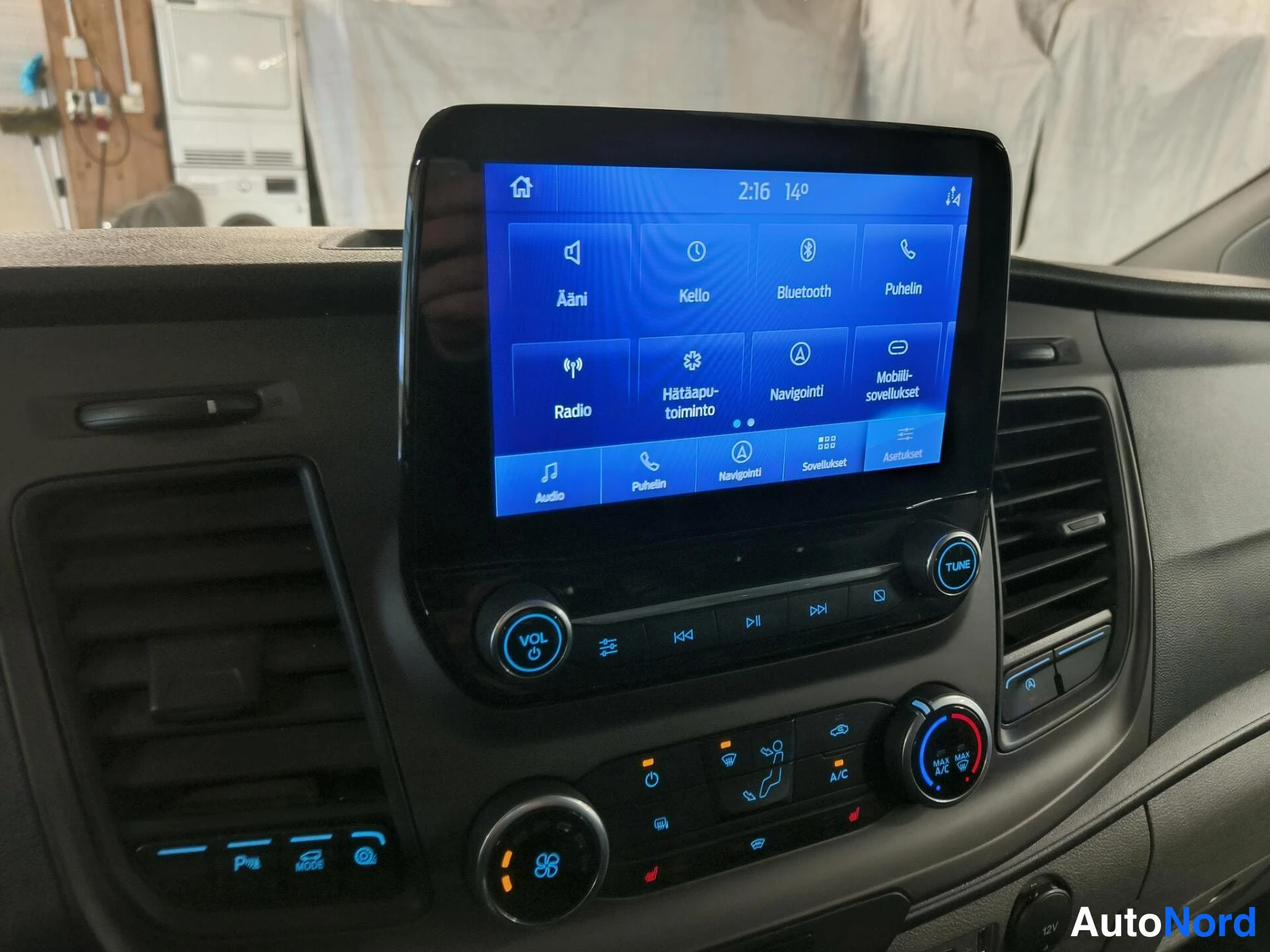 Muu: Infotainment-näyttö suomalaisilla valikoilla (Ääni, Kello, Bluetooth, Puhelin, Radio, Navigointi) ja alla A/C-säädöt.
