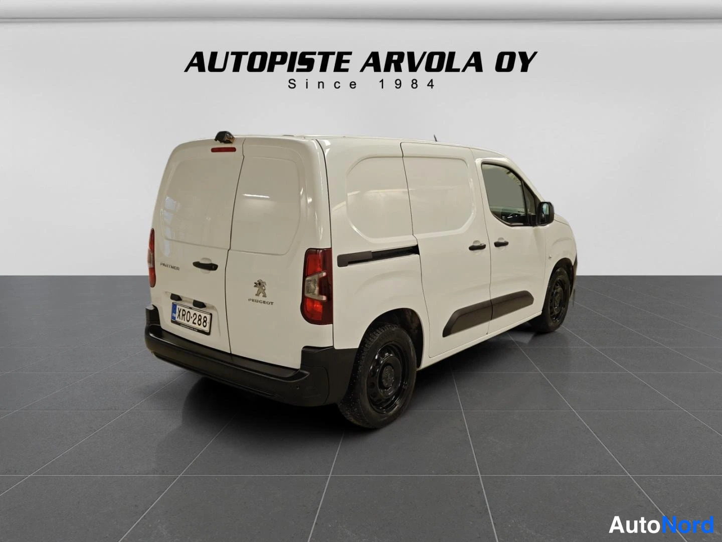 Takaviisto: Peugeot Partner takaosa vinosti vasemmalta valkoinen pakettiauto, rekisterikilpi.