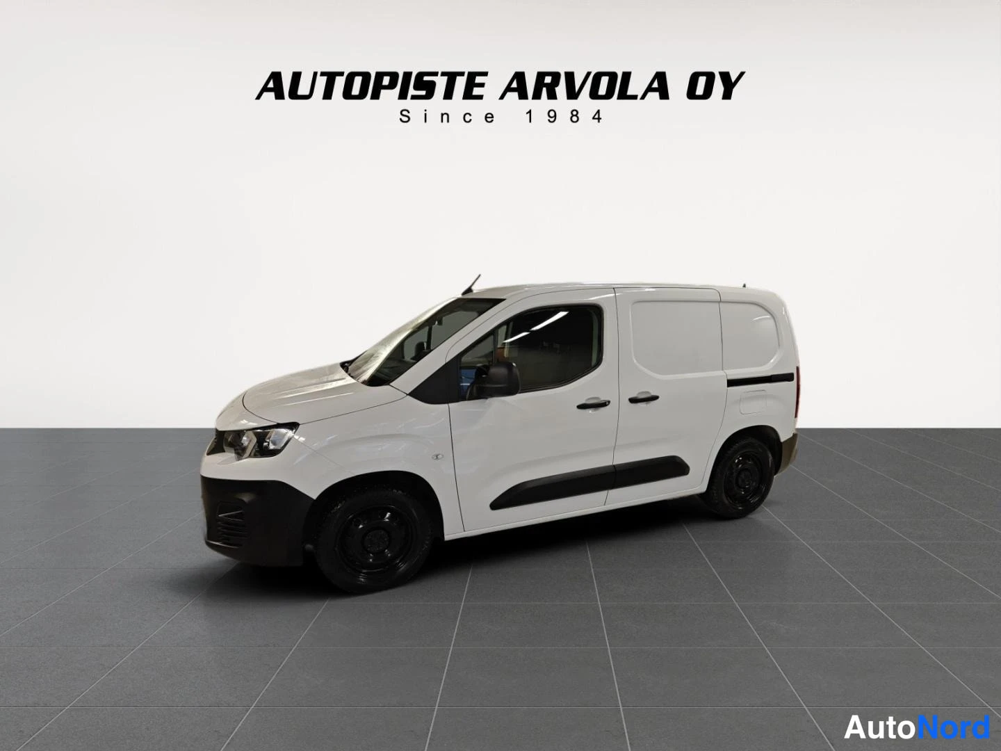 Etuviisto, nokka vasemmalle: Peugeot Partner -pakettiauto valkoisena studiotietta vasten, kylki- ja keulanäkyvasemman; Autopiste Arvola OY: Since 1984 -teksti taustalla.