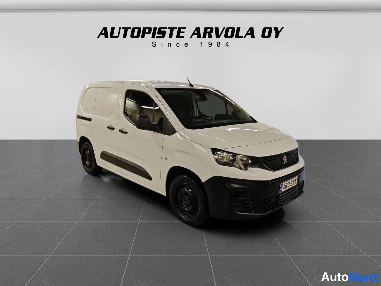 Etuviisto, nokka oikealle: Valkoinen pakettiauto etukulmasta oikealta, keulalla Peugeoton merkki ja rekisterikilpi XR0-288.
