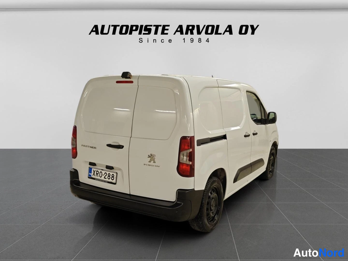 Takaviisto: Valkoinen pakettiauto takakulmasta vasemmalta, takana kaksi ovea, Peugeot-logo ja rekisterikilpi XR0-288.