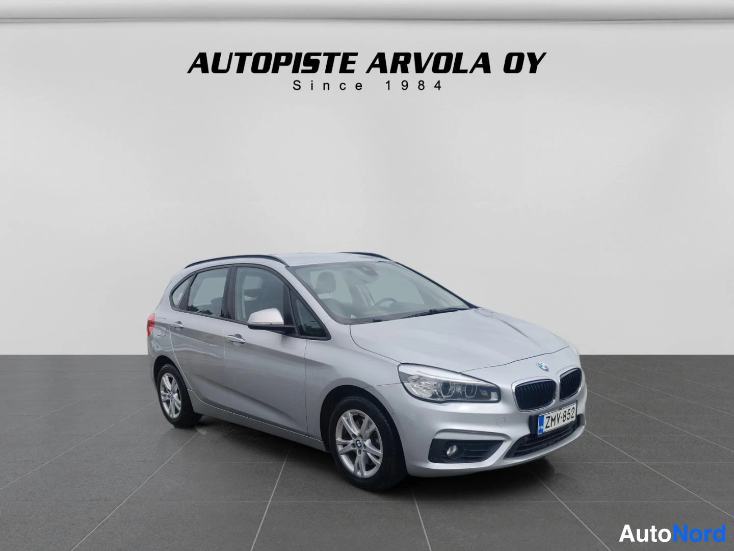 Etuviisto, nokka oikealle: BMW Active Tourer -farmarimallinen auto hopeanhohtoisena kulmassa edestä vasemmalta, rekisterikilpi.