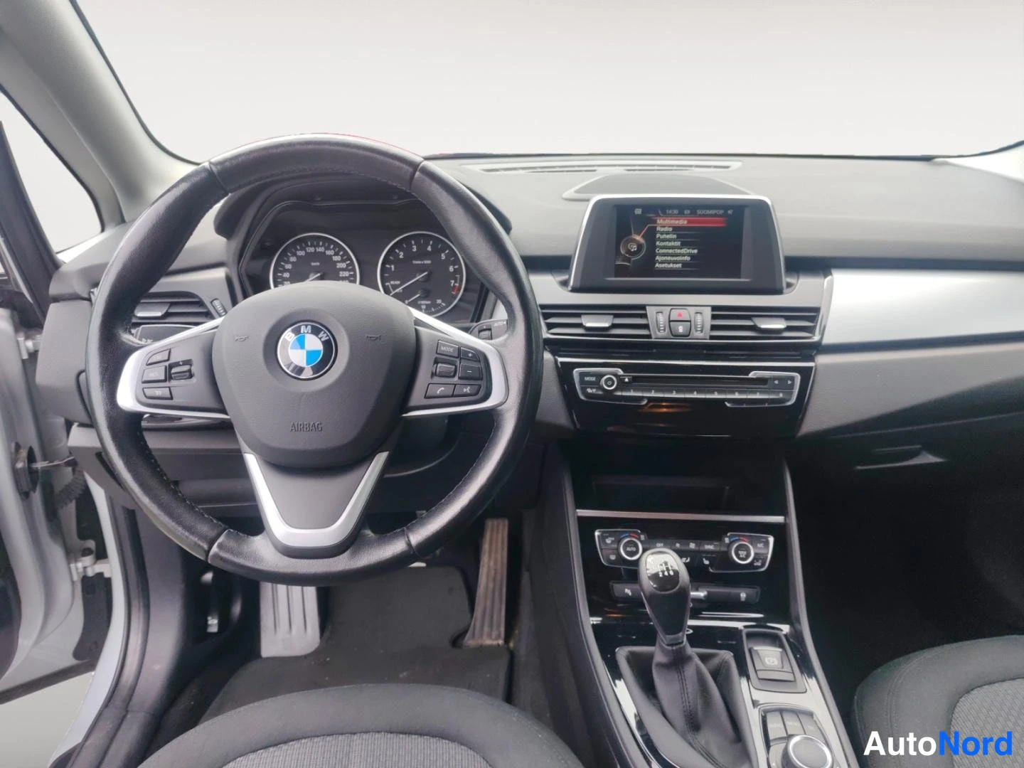 Muu: Autojen ohjaamo: BMW-ohjauspyörä, analogiset mittarit, keskikonsolilla manuaalivaihde ja näyttö.