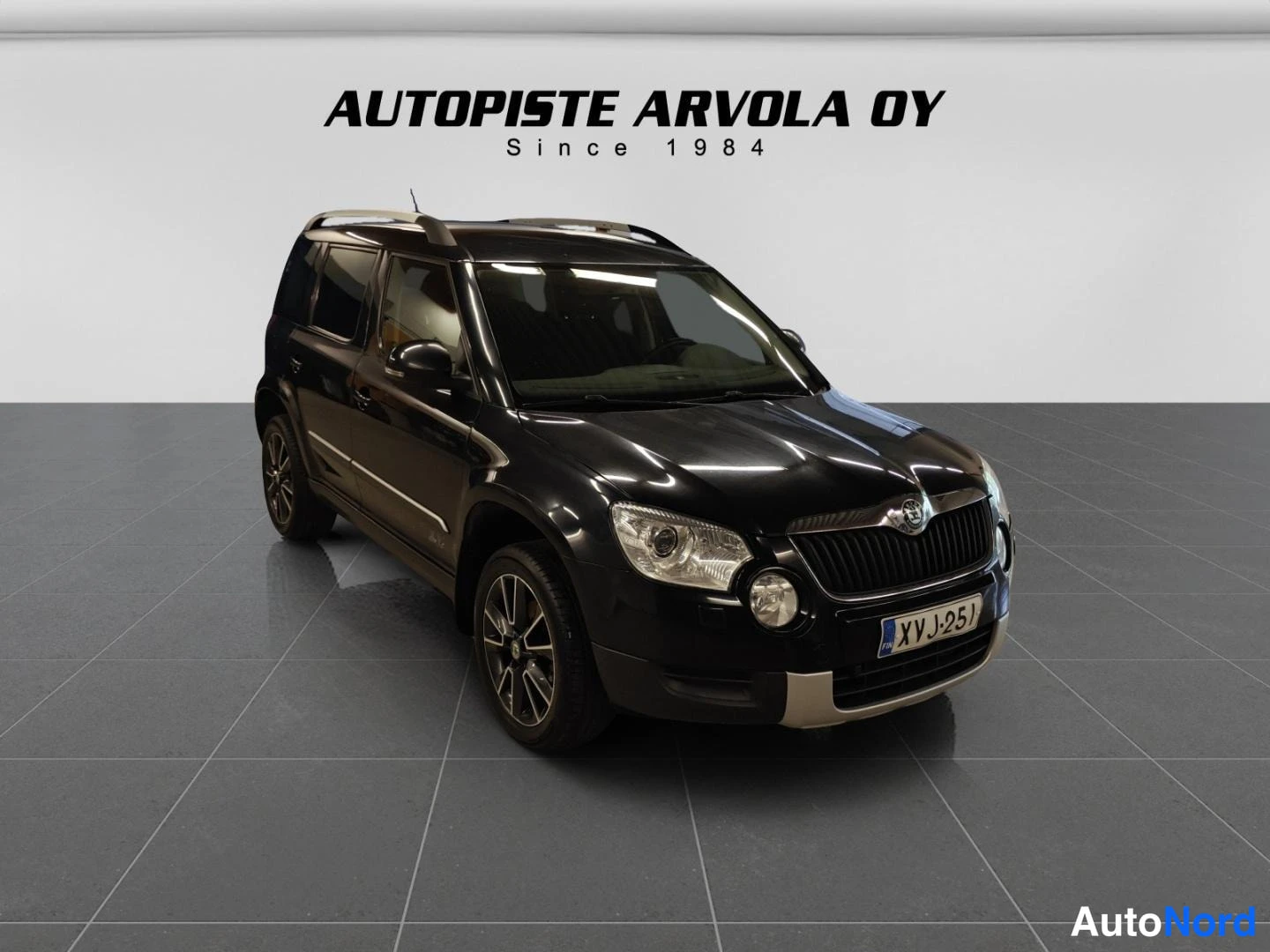 Etuviisto, nokka oikealle: Auton etukoispästä kuva; musta Skoda Yeti, hopeiset kattokaiteet ja kevytmetallivanteet.
