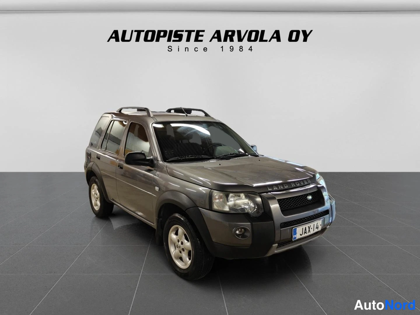 Etuviisto, nokka oikealle: Land Rover Freelander etuviistossa vasemmalta kuvattuna, tummanharmaa kori, kattokaiteet ja rekisterikilpi.