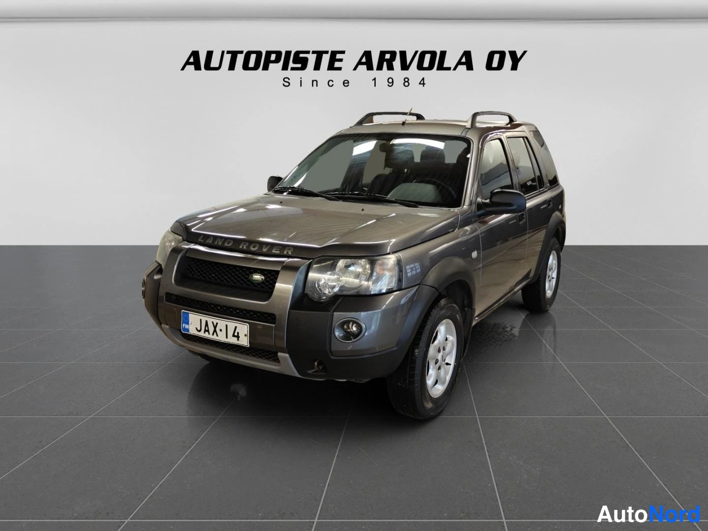 Etuviisto, nokka vasemmalle: Auton etukulma kuvattuna vasemmalta: konepellillä LAND ROVER -teksti, rekisterikilpi.
